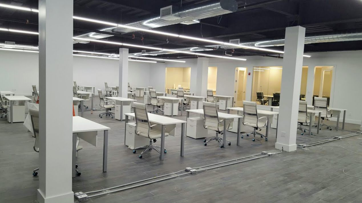 A space with a lot of white tables and white office chairs